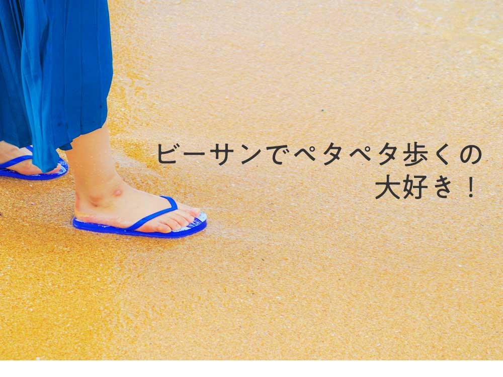 砂浜でビーチサンダルを履いている女性の足
