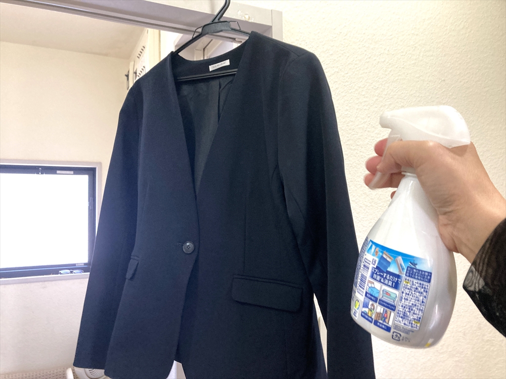 服にスプレータイプの消臭剤を吹きかけている様子