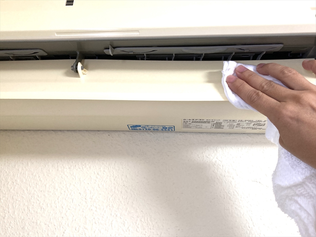 エアコンのルーバー部分をタオルで拭きとっている様子