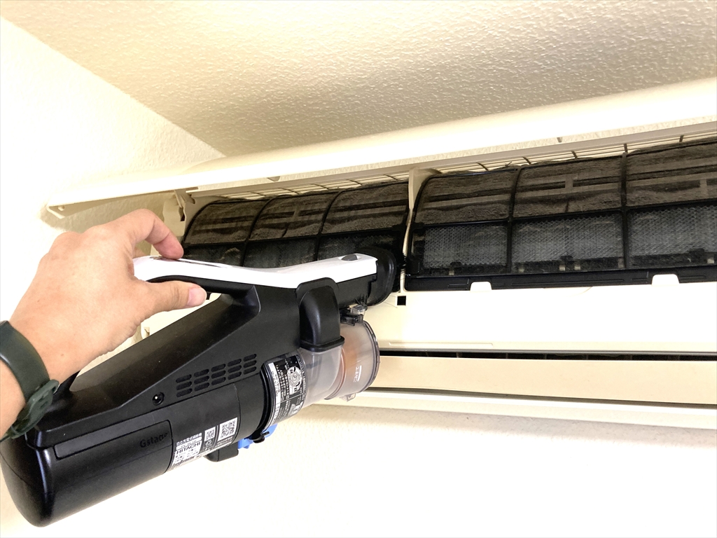 エアコンフィルターの埃を掃除機で取り除いている様子