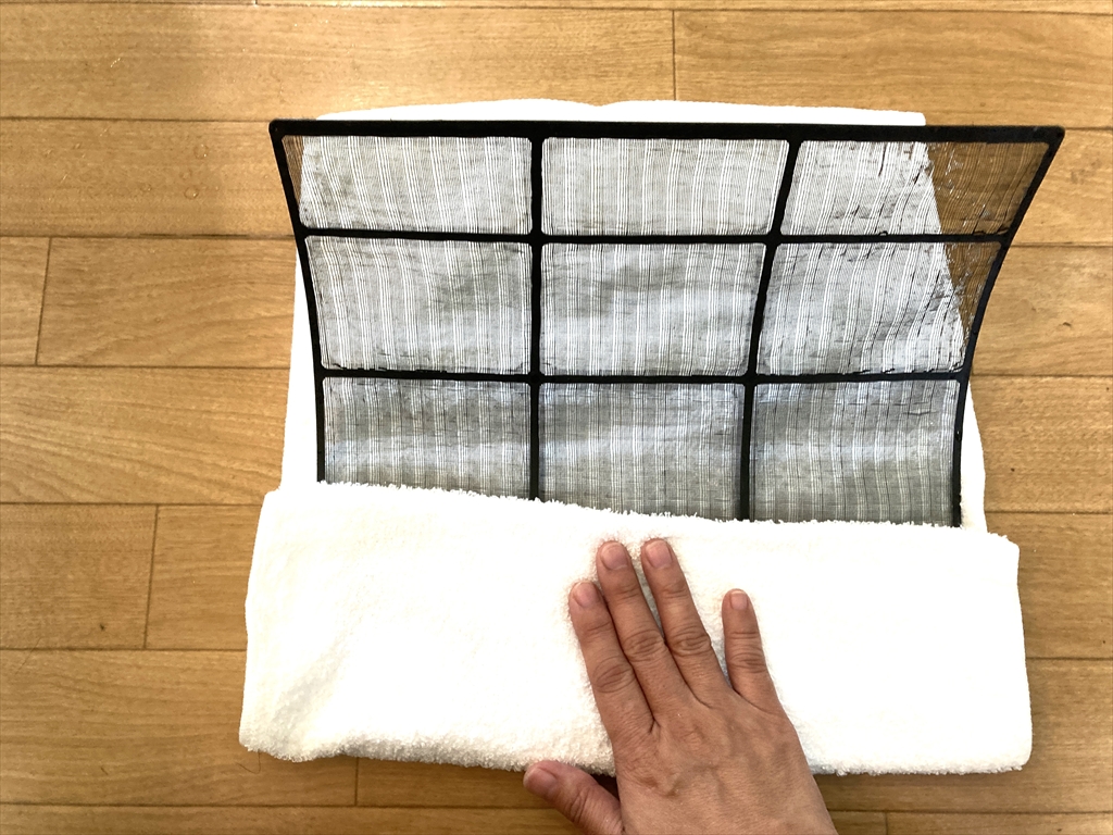 エアコンフィルターの水気をタオルで取り除いている様子