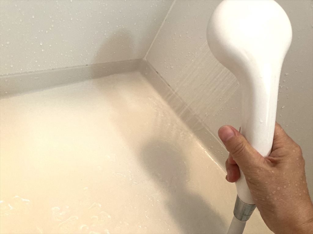 シャワーでカビ掃除をした場所を洗い流している様子