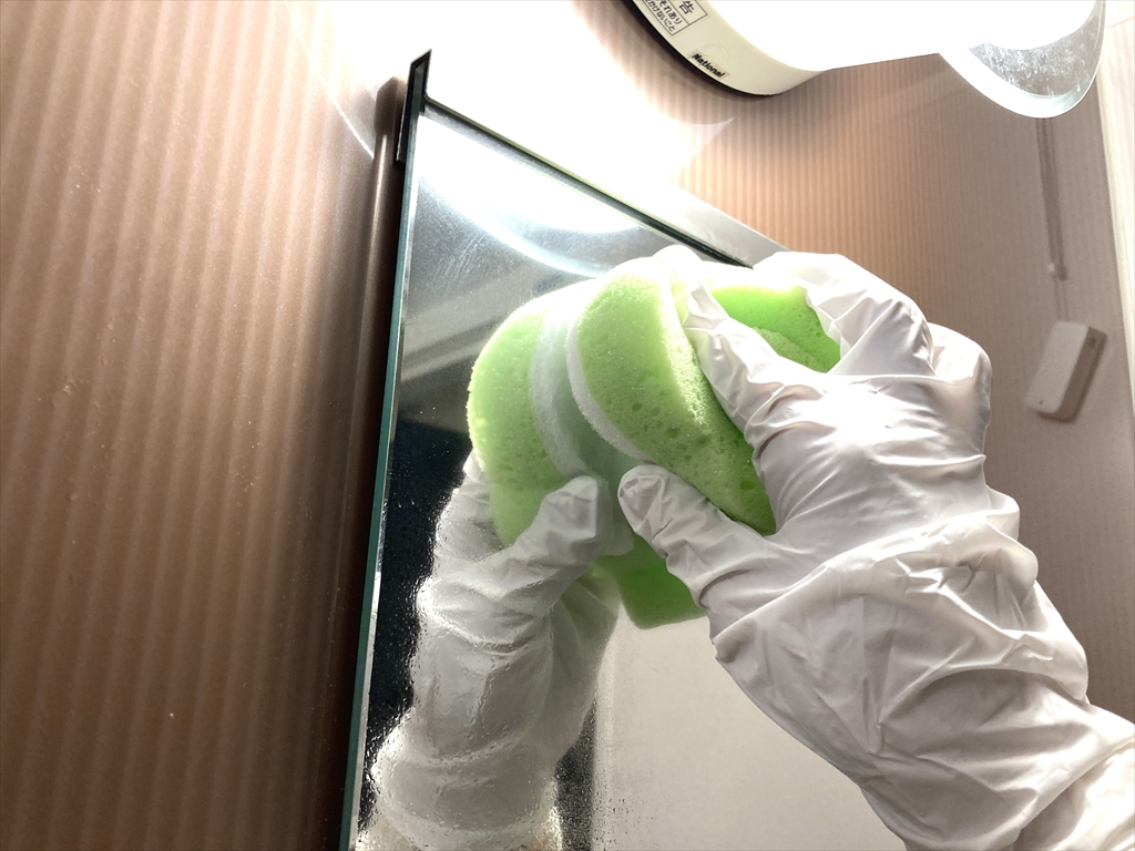 鏡をスポンジでこすり洗いしている様子