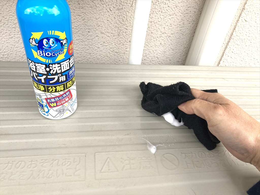 エアコン室外機の上部についた汚れを、バイオサイクル泡洗剤を使って拭きとっている様子