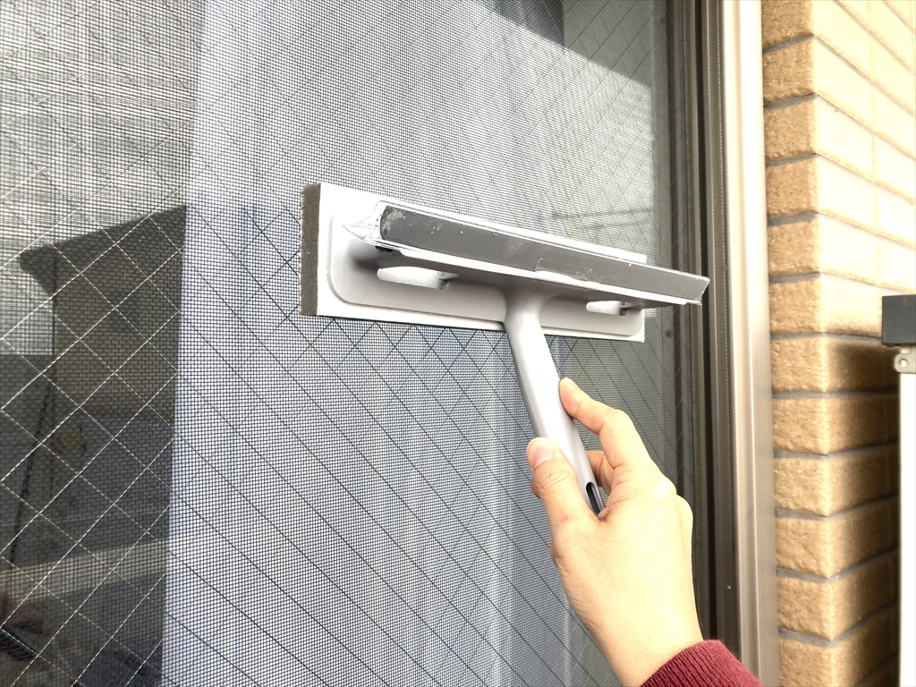 窓・網戸クリーナーのブラシ部分で網戸をこすっている様子