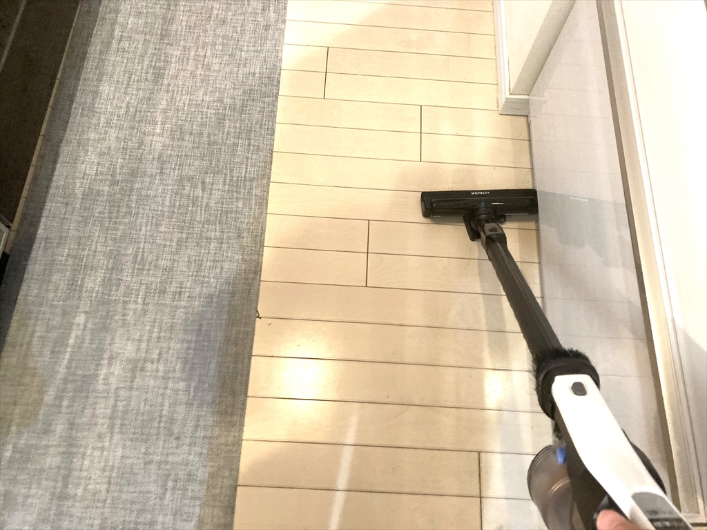 キッチンの床を掃除機で掃除しているところ