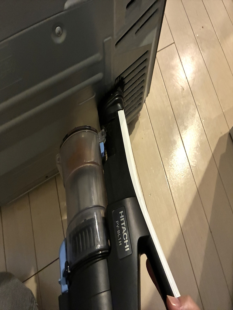 冷蔵庫裏にある通気口に掃除機をあてて、ホコリを吸い出している様子