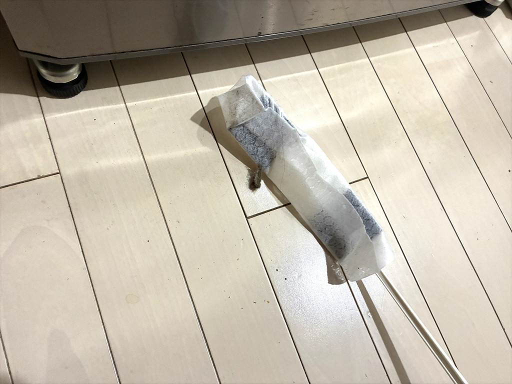 冷蔵庫の下に隙間らくらくハンディワイパーを入れてホコリをかきだしている様子