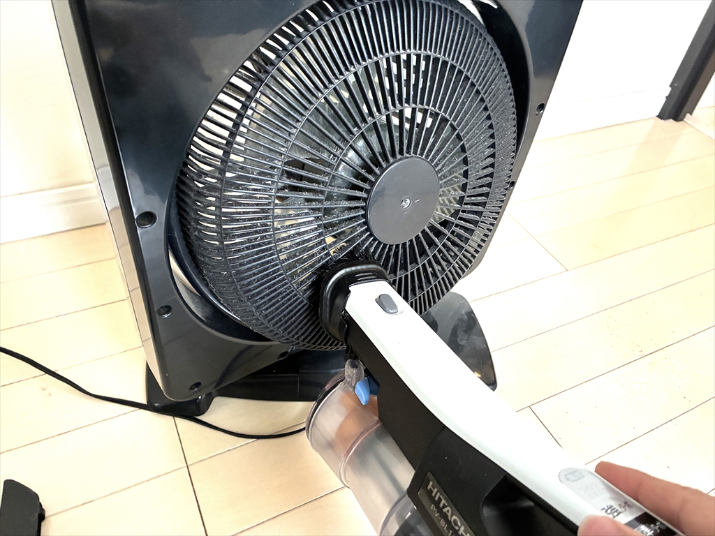 カバーが取り外せないタイプのサーキュレーター。前面から掃除機でホコリを吸い出している様子