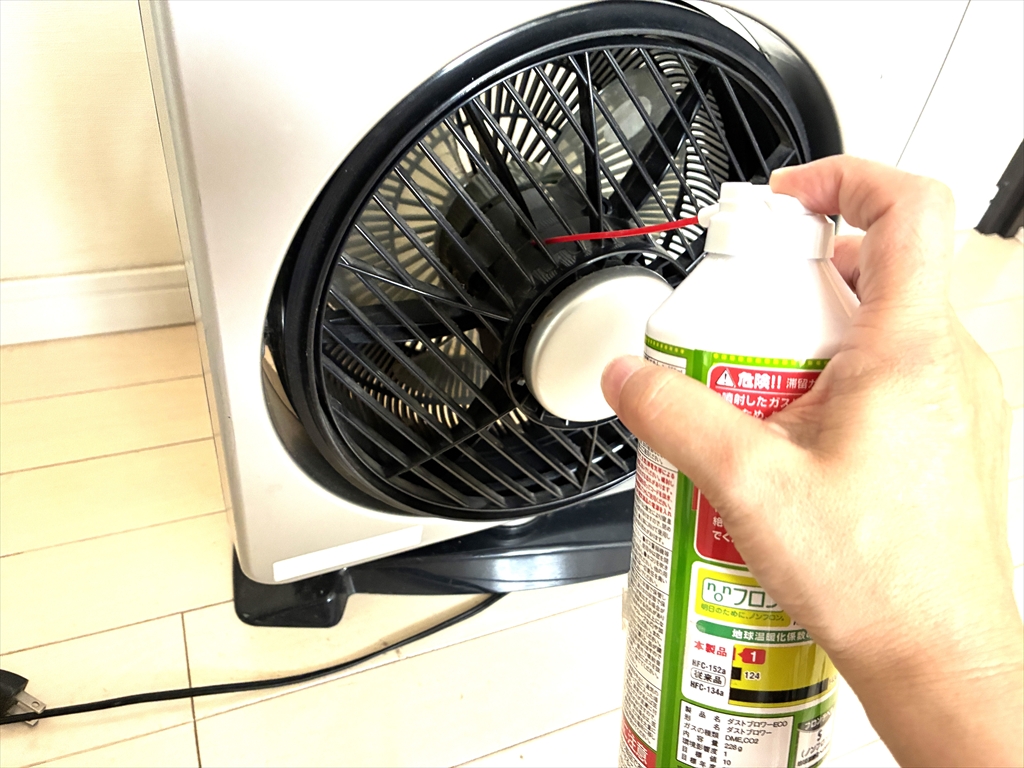 カバーが外れないサーキュレーターの前面から、エアダスターを噴射してホコリを吹き飛ばしている様子
