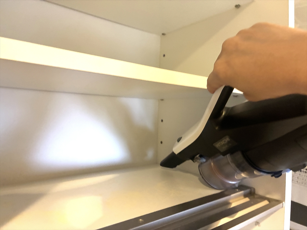 食器棚の中をハンディ掃除機でお掃除している様子